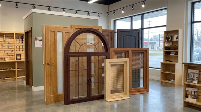 Showroom display of wood doors, an arched window, and shutter samples