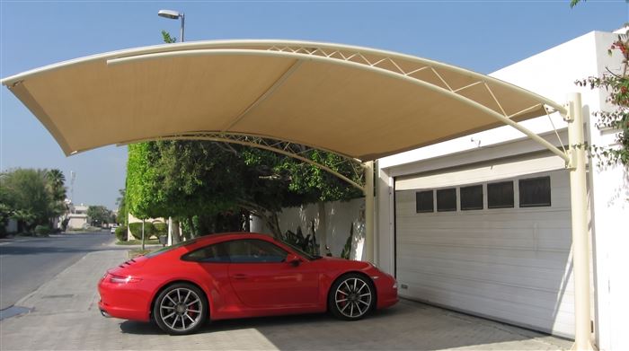 Curved fabric carport shade beside a villa garage