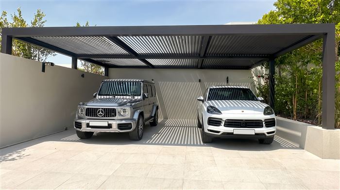 Modern louvered aluminum carport over two SUVs