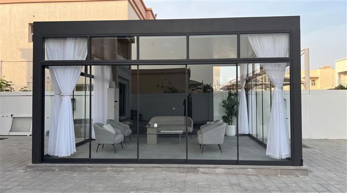 Modern glass majlis with sheer curtains and lounge seating